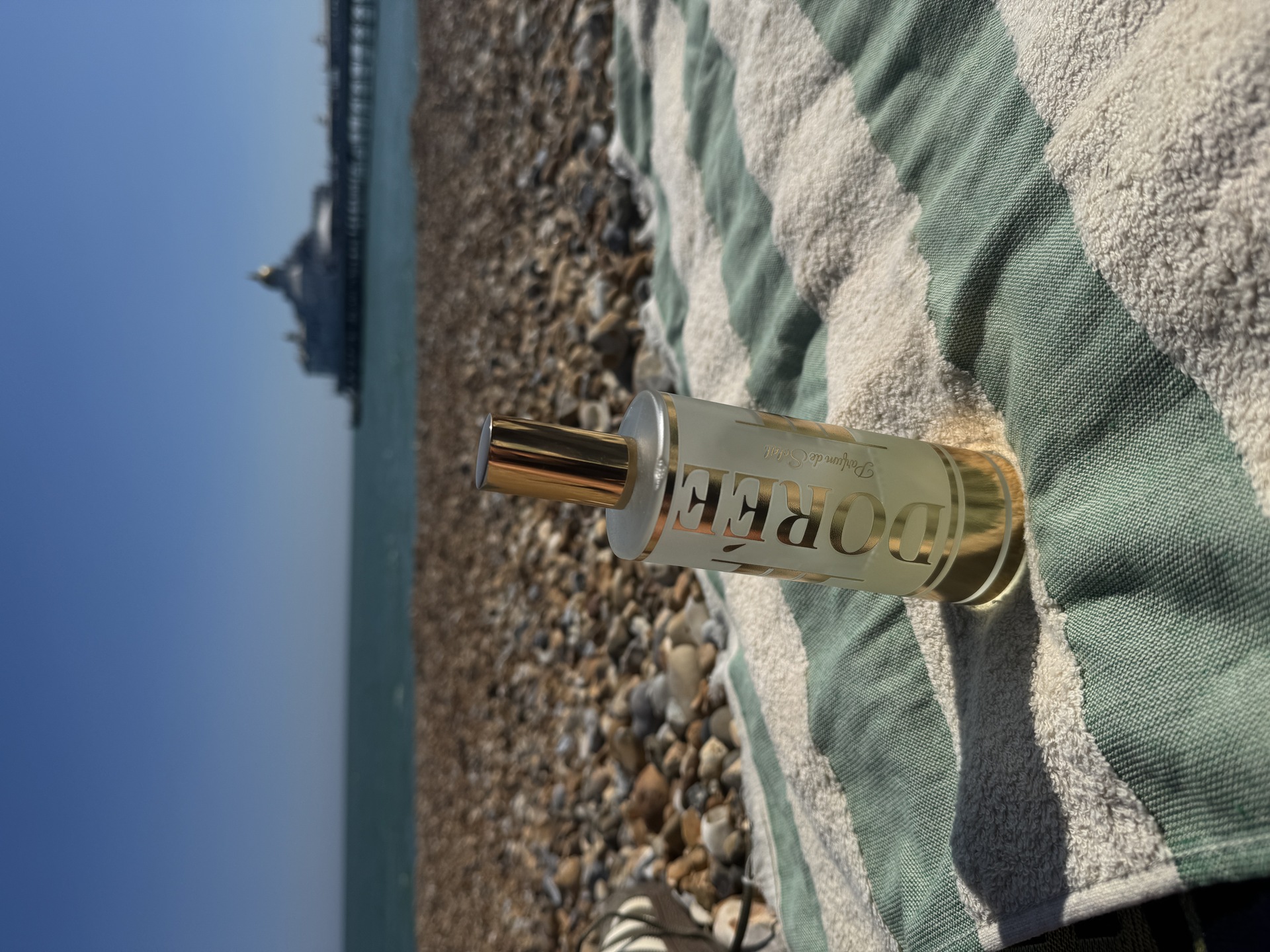 Dorée sunscreen on beach towel with pier