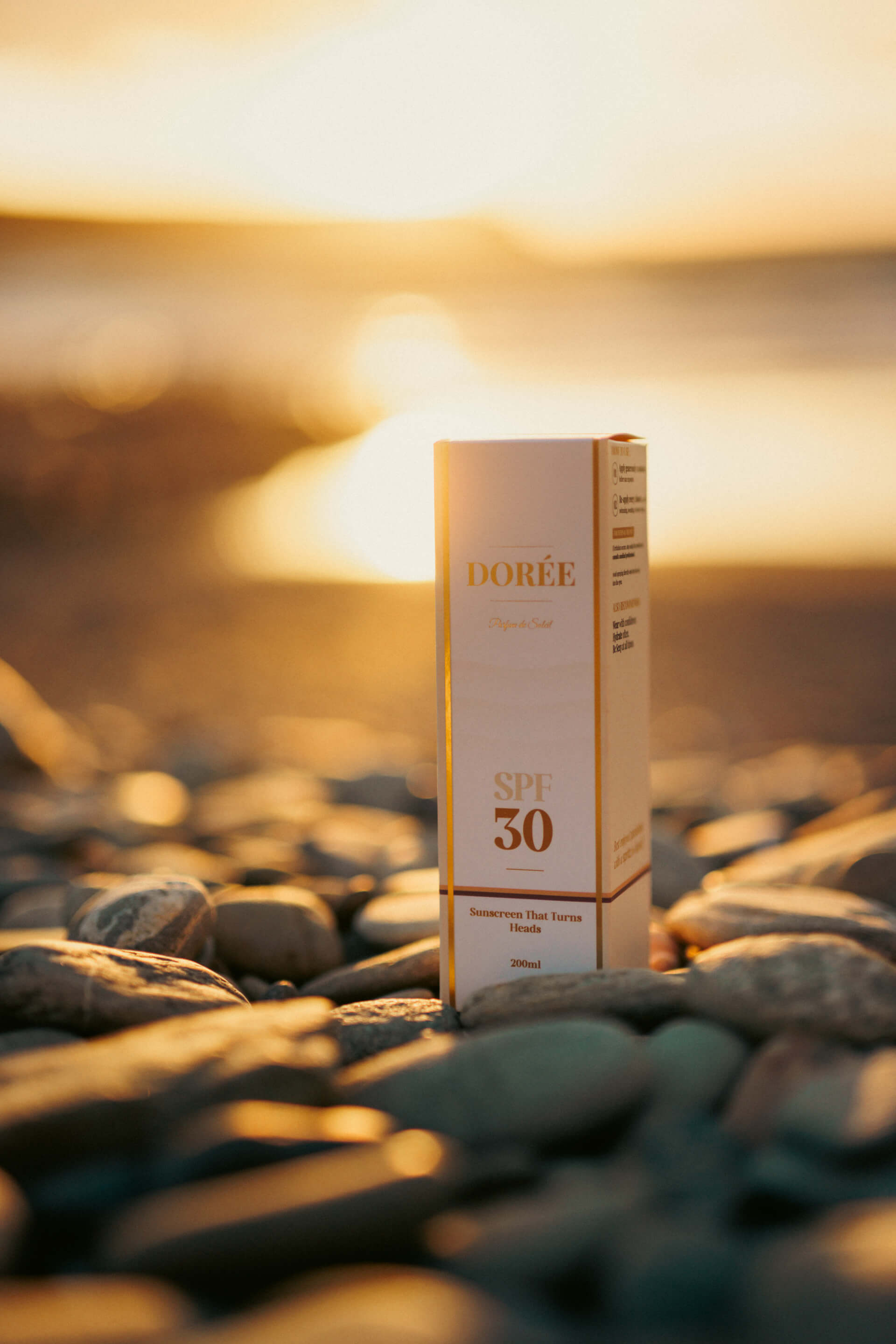 Dorée packaging on pebble beach at golden hour